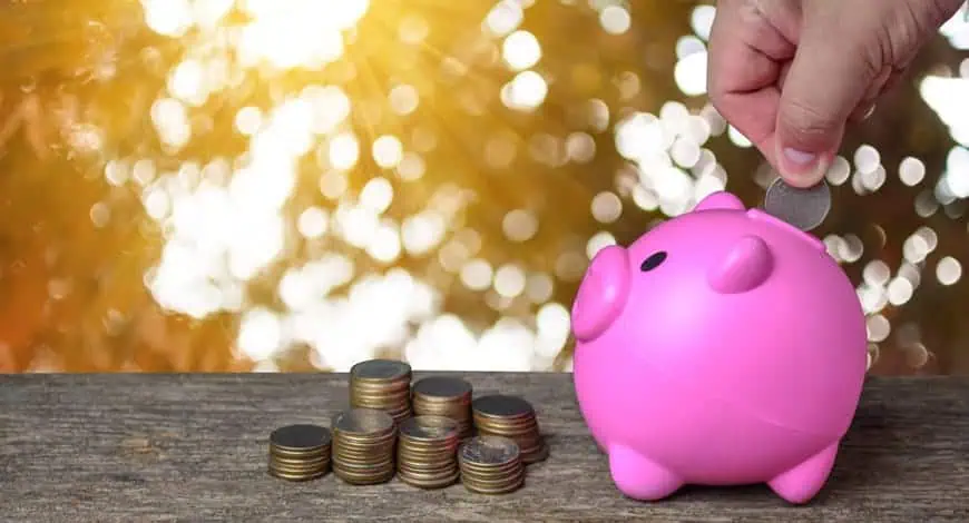 hand putting coins in piggie bank