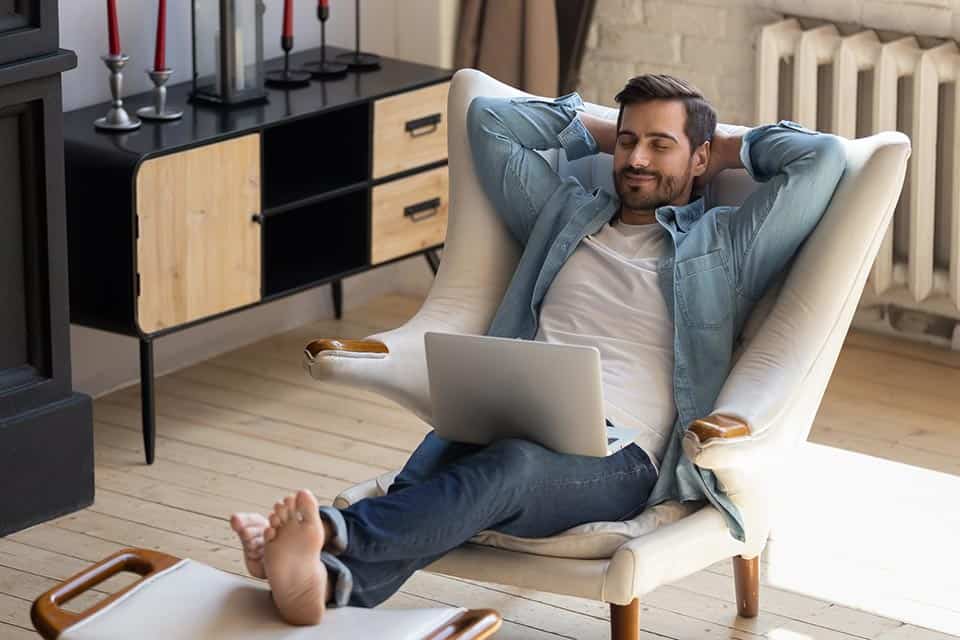 happy man lounging with a laptop