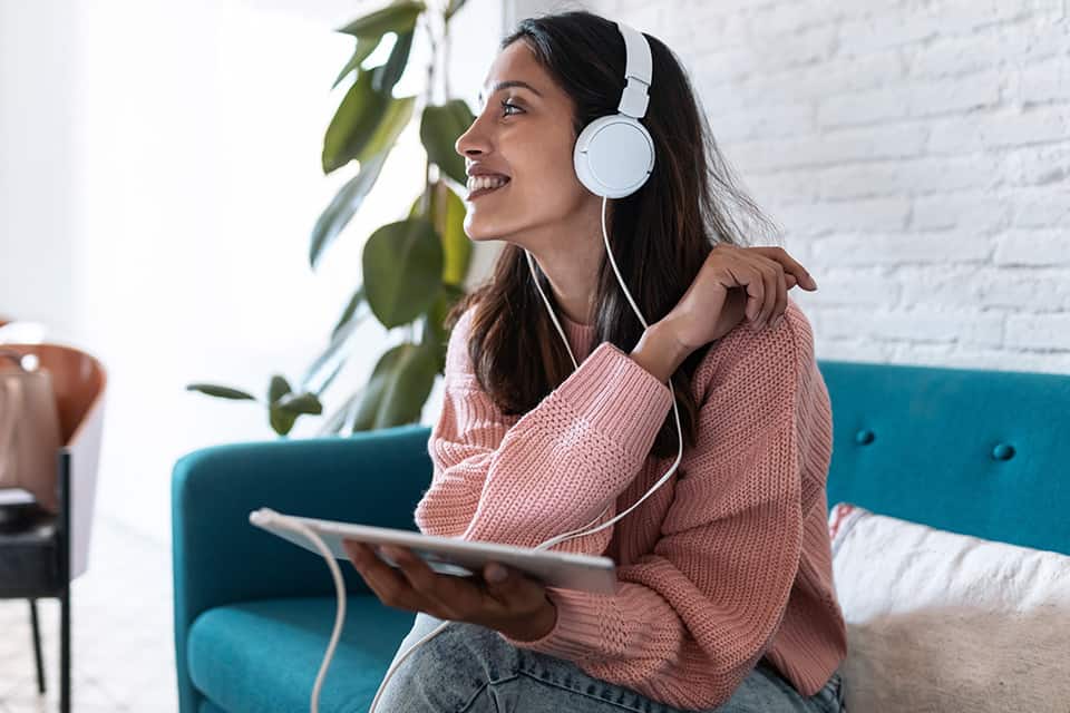 woman wearing headphones with a tablet