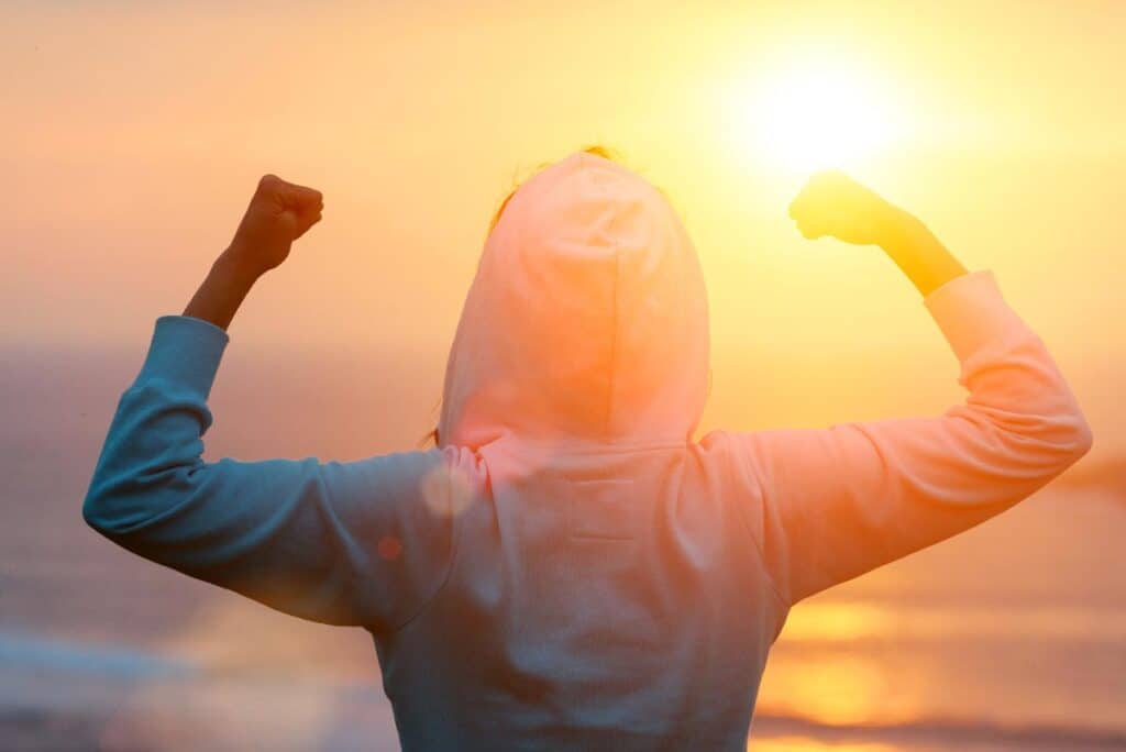 person on beach flexing in a hoodie