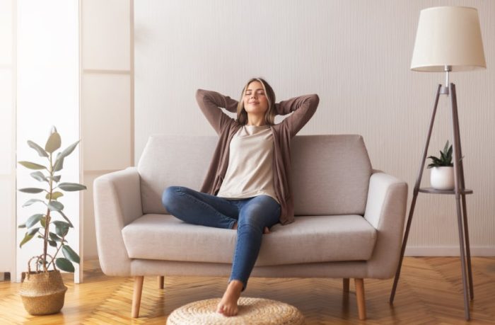 Finally weekends. Millennial girl relaxing at home on couch, enjoying free time, empty space